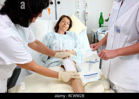 Krankenschwestern die Behandlung eines Patienten in einem Krankenhausbett ändern Stockfoto