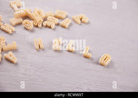 Text Hallo mit Makkaroni in Form von Buchstaben auf grauem Holz- Tabelle geschrieben Stockfoto