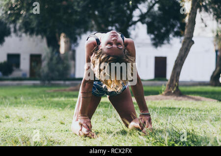 Yoga - draußen junge Schöne schlanke Frau Yoga Lehrer tun Kamel Ustrasana asana Übung im Freien dar. Vintage Retro wirksam gefiltert Hipster style Bild. Stockfoto