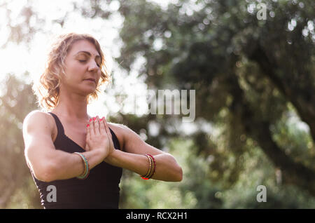 Schöne junge Frau meditiert im Yoga Asana Padmasana-Lotus auf der Holzterrasse im Herbst Park darstellen. Stockfoto