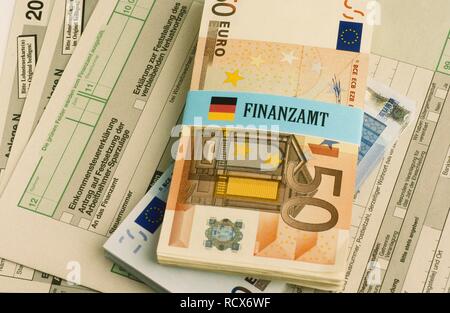 Bündel von Euro-banknoten gebunden mit einem Etikett für Finanzamt, Deutsch für Finanzamt, Einkommenssteuererklärung Formulare Stockfoto