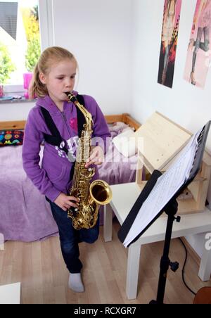 Mädchen, 10 Jahre, üben Saxophon in Ihrem Zimmer Stockfoto