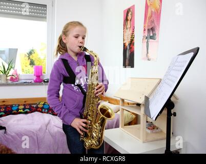 Mädchen, 10 Jahre, üben Saxophon in Ihrem Zimmer Stockfoto