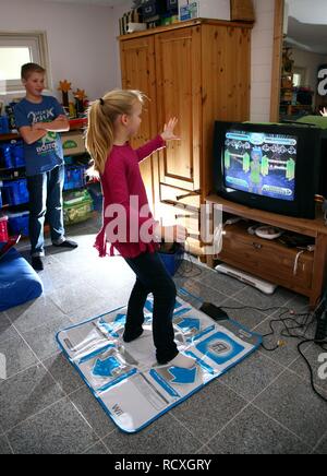 Geschwister, ein Junge, 12 Jahre alt, und ein Mädchen, 10 Jahre alt, spielen, Tanz Spiel auf Wii Spiele in Ihrem Zimmer Konsole zusammen Stockfoto
