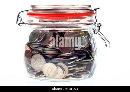 Jar verwendet als Sparschwein mit Münzen aus verschiedenen Ländern Stockfoto