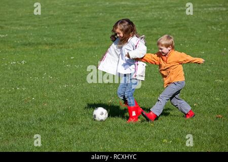 Mädchen und junge spielt Fußball Stockfoto