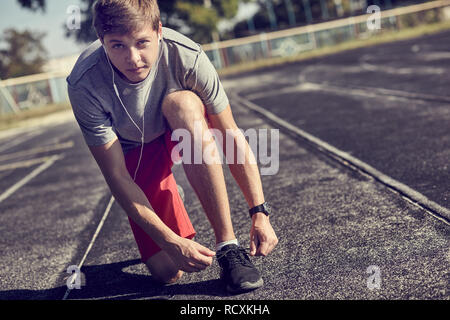 Mann schnürung Sport Schuhe zur Vorbereitung auf die Ausbildung bei Sonnenaufgang Stockfoto