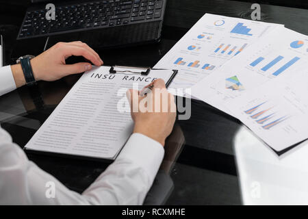 Junger Mann zeichen Versicherung im hellen Büro Stockfoto