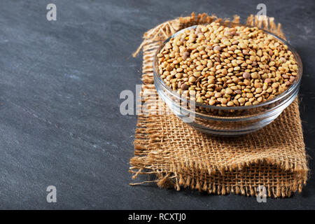 Roh Linsen auf Schwarz Stein Hintergrund. Gesunde vegetarische Essen Konzept. Superfoods. Kopieren Sie Platz. Linsen sind reich an komplexen Kohlenhydraten, Ballaststoffen, hohe Stockfoto