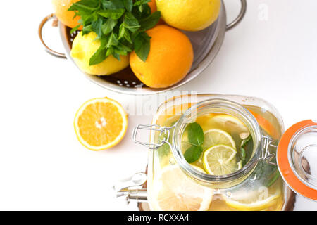 Gesunde Limonade in großen Marmeladenglas mit Zitrone, Orange und Minze auf weißer Tisch. Close Up. Stockfoto