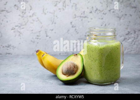 Smoothies avocado Banane in ein Marmeladenglas, Bananen und Avocados auf grauem Beton Hintergrund Stockfoto