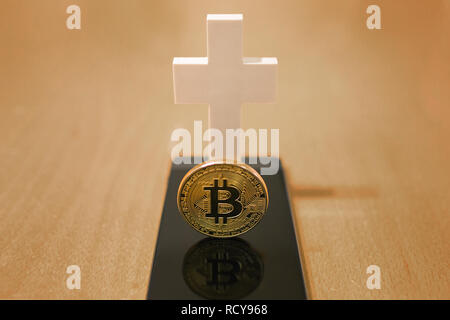 Tot Bitcoin Konzept mit einem weißen Kreuz und Smartphone als Grab Stockfoto