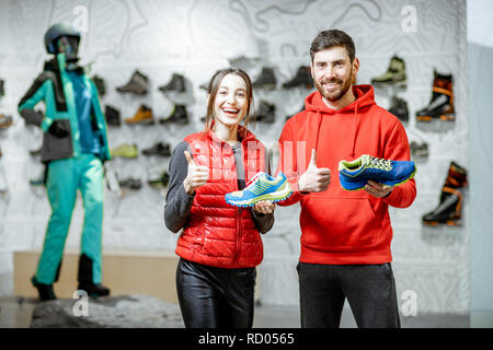 Porträt eines lächelnden Mann und Frau stehend mit Schuhe zum Wandern im modernen Sport Shop Stockfoto