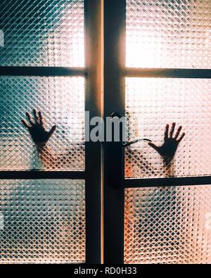 Beleuchtete Silhouette der Hände, Berühren eine Glastür Stockfoto