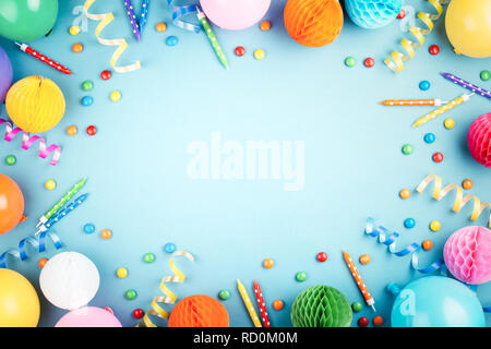 Geburtstag Hintergrund auf Blau. Ansicht von oben. Rahmen aus bunten Serpentine, Luftballons, Kerzen und Süßigkeiten. Stockfoto