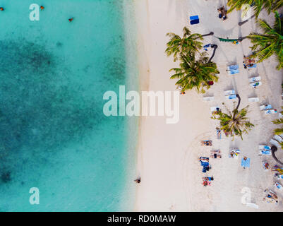 Schöner Strand mit weissem Sand, Palmen und dem klaren, blauen Meer. Menschen Sonnen und Schwimmen, Ansicht von oben. Stockfoto