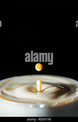 High speed Foto einer Karamell Milch Tropfen auf schwarzen Hintergrund im Studio Stockfoto