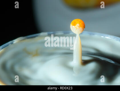 High speed Foto einer Karamell Milch drop auf dunklem Hintergrund im Studio Stockfoto