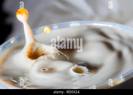 High speed Foto einer Karamell Milch drop auf dunklem Hintergrund im Studio Stockfoto