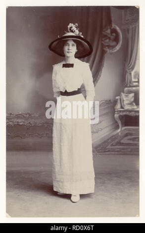 Originale, klare Porträtpostkarte aus der Zeit des 1. Weltkriegs von einer schönen, eleganten jungen Frau namens Blanche, die ein schönes weißes Sommerkleid und einen schwarzen Hut mit breiter Krempe trägt, datiert vom 20. Juli 1914, Großbritannien Stockfoto