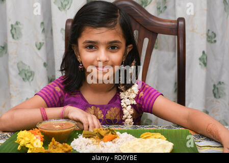 Indisches Mädchen Kind essen Onam Sadhya grand Fest diente auf bananenblatt mit Hand auf Onam, Vishu Harvest Festival von Kerala, Indien. Stockfoto