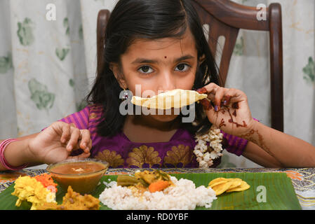 Indisches Mädchen Kind essen Onam Sadhya grand Fest diente auf bananenblatt mit Hand auf Onam, Vishu Harvest Festival von Kerala, Indien. Stockfoto