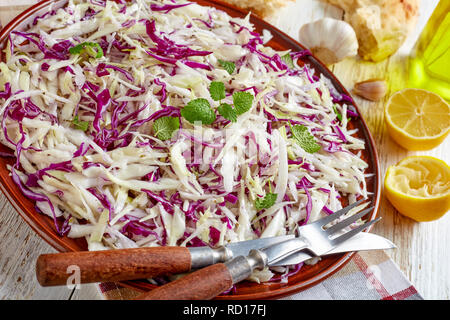 In der Nähe der Libanesischen zerkleinerte Kohl Salat, malfouf Salat mit Zitronensaft, Olivenöl, Knoblauch, getrocknete und frische Minze in einem irdenen Schüssel auf eine napki Stockfoto