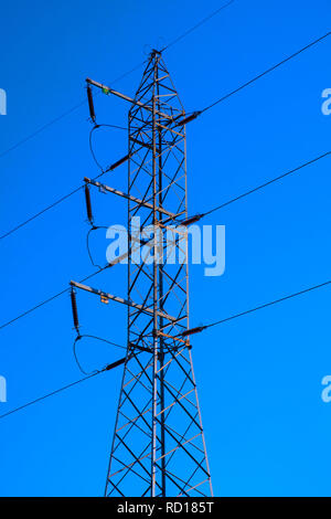 Hochspannungsleitung durch das Metall Bau einer Hochspannung elektrische Pole mit Power Isolatoren und Anschlüsse in einem tiefen Blau unterstützt. Stockfoto