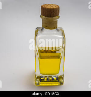 Transparent rechteckige Glas Flasche mit einem Korken verschlossen. Zur Hälfte gefüllt mit einem gelb leuchtenden Flüssigkeit, vor einem weißen Hintergrund ausgesetzt. Stockfoto