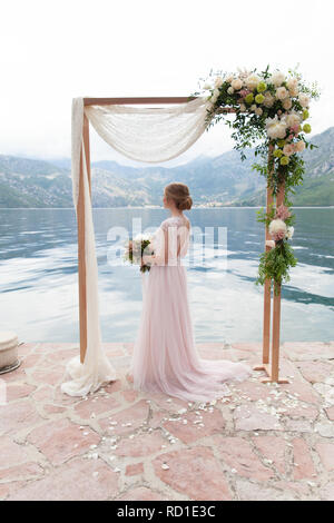 Schöne hölzerne Hochzeit Bogen mit Blumen im Freien und die Braut eingerichtet Stockfoto