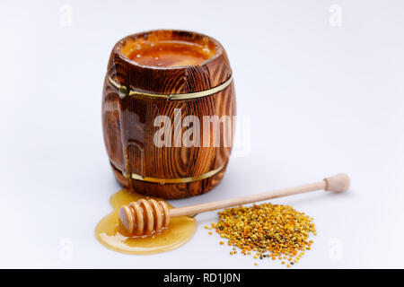 Duftende frische Honig fließt vom Fass und Honig Stick in einen Tropfen Honig mit einer Handvoll Pollen auf einem weißen Hintergrund. Isoliert. Stockfoto