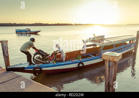 Laden von einem Moped auf einem traditionellen Boot auf den Suriname Fluss Stockfoto