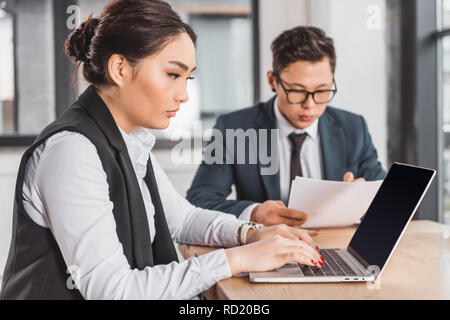 Junge kasachische Geschäftsleute arbeiten mit Laptop und Unterlagen im Büro ausgerichtet Stockfoto