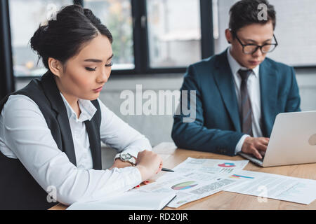 Professionelle junge kasachische Unternehmen arbeitenden Menschen mit Papieren und Laptop im Büro Stockfoto