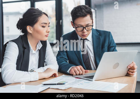 Konzentrierte sich junge Kollegen arbeiten mit Laptop und Unterlagen im Büro Stockfoto