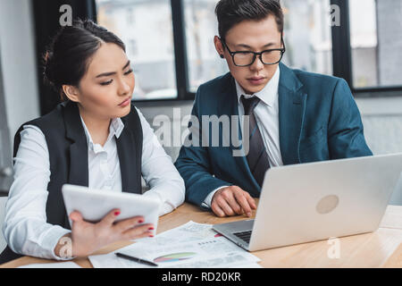 Schwere jungen kasachischen Geschäftsleute arbeiten mit Laptop und einer Tablette im Büro Stockfoto