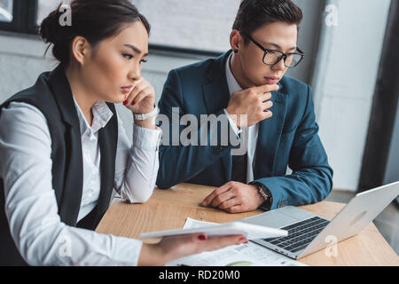 Konzentrierte junge Geschäftsleute arbeiten mit Laptop und einer Tablette im Büro Stockfoto