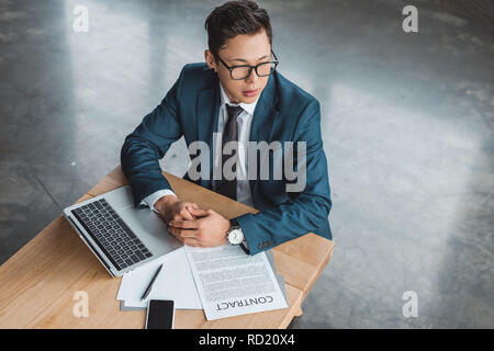 Hohe Betrachtungswinkel von Stattlichen konzentrierte jungen kasachischen Geschäftsmann am Arbeitsplatz sitzen Stockfoto