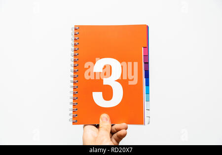 Männliche hand Notebook mit großen Anzahl 3 gedruckt auf orange Farbe für Präsentation oder Business bereit, etc. Stockfoto