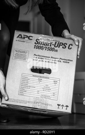 PARIS, Frankreich, 29.MÄRZ 2018: Leistungsfähige IT Frau unboxing C APC Smart-UPS 1000VA LCD 230V auf Unternehmensebene, unterbrechungsfreie Stromversorgungen von American Power Conversion office Holzboden - Schwarz und Weiß Stockfoto