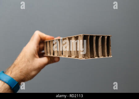 Arbeiter männlichen Hand gegen grauen Hintergrund eine Wellpappe Karton Papier für die Verpackung Stockfoto