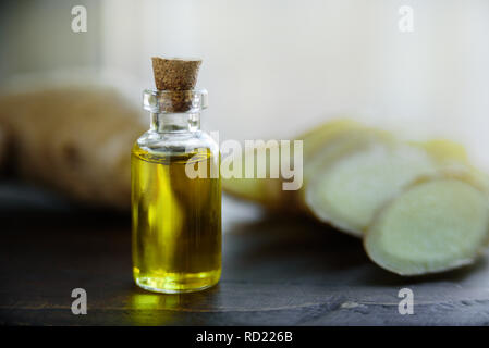 Flasche Ingwer Öl. Ingwer Wurzel auf Hintergrund, grüne Blätter Stockfoto