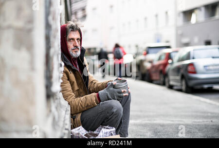 Obdachlose Bettler sitzen draußen in der Stadt bitten um Geld Spende. Stockfoto