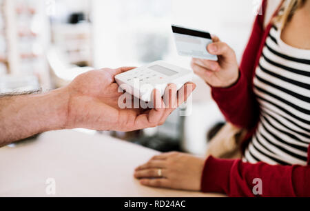 Kunden und Verkäufer, kontaktlose Zahlung mit Kreditkarte in einem Shop. Stockfoto