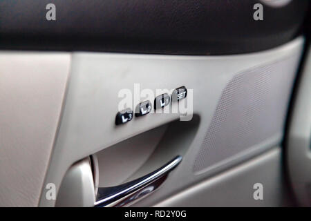 Automatische Tasten mit weißen Zeichen und Symbole in einer Reihe über der Chrom befinden, Griff der Seitentür des Autos, das Panel ist Shea Stockfoto