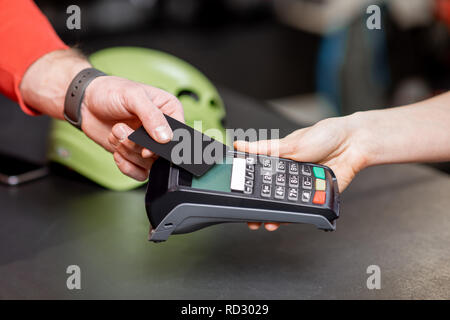 Mann, der Kauf mit Bankkarte und Kasse in den Zähler der Sport Shop, Nahaufnahme Stockfoto