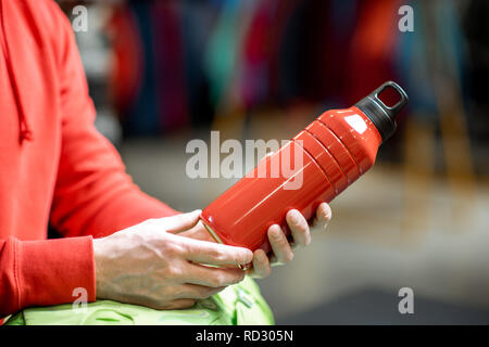 Mann mit roten Thermoskanne für Wandern im Sportgeschäft, Nahaufnahme Stockfoto