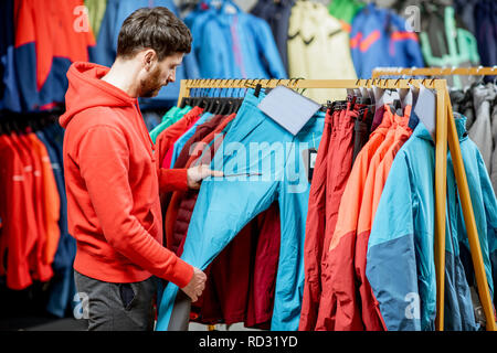 Mann Auswahl Winterkleidung Abholung Hose auf dem Bügel im Sportgeschäft Stockfoto