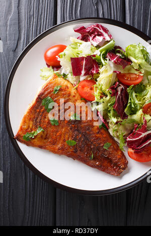 Gebratenes Zanderfilet mit frischem Salat in der Nähe serviert auf einem Teller. Vertikal oben Ansicht von oben Stockfoto