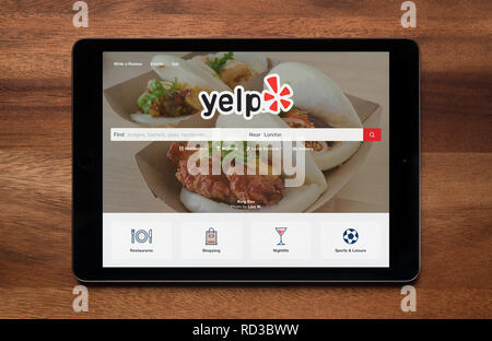 Die Website von Yelp gesehen auf einem iPad Tablet, der ruht auf einem Holztisch (nur redaktionelle Nutzung). Stockfoto